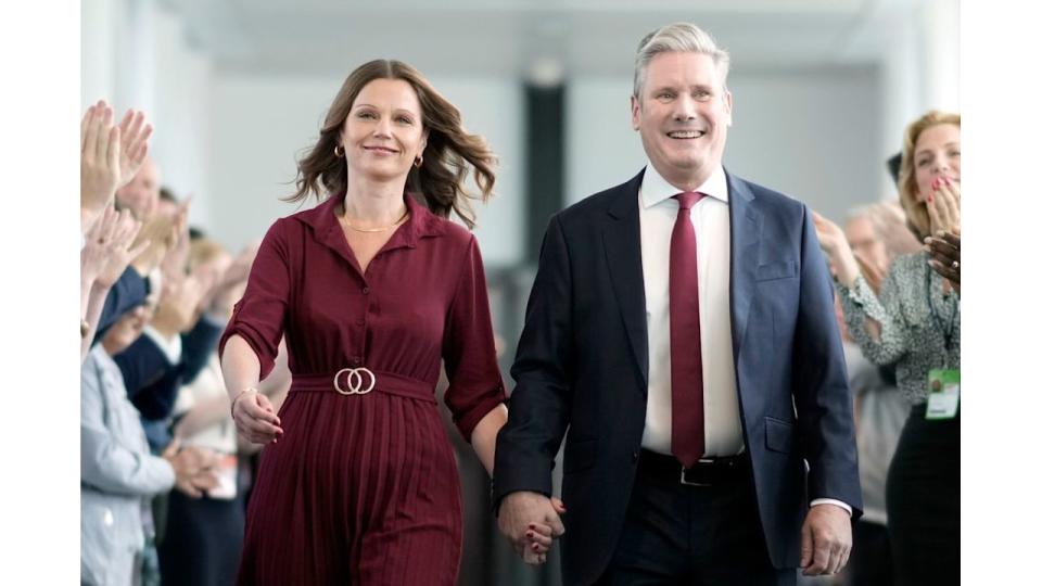 Keir Starmer holding hands with his wife Victoria, who wears a maroon dress