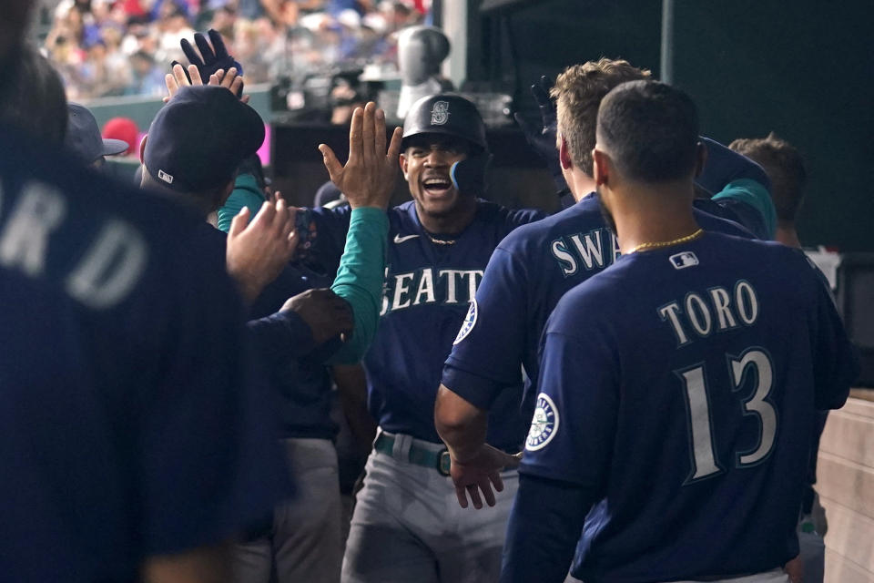 Seattle Mariners' Julio Rodriguez, center, celebrates in the dugout after Rodriguez hit a grand slam in the eighth inning of the team's baseball game against the Texas Rangers, Friday, July 15, 2022, in Arlington, Texas. (AP Photo/Tony Gutierrez)