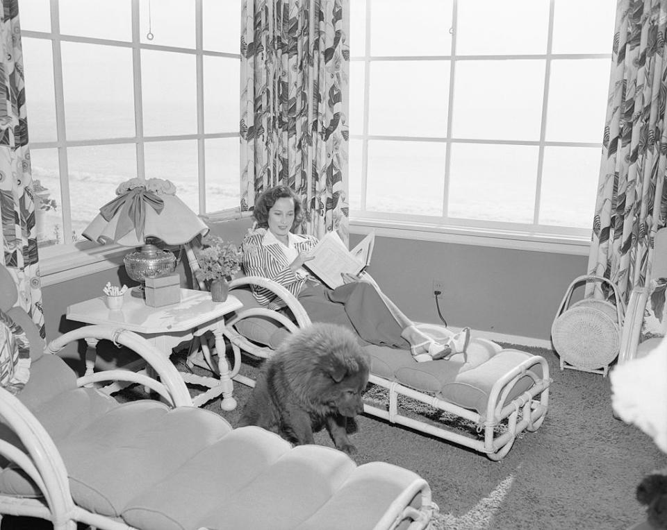 <p>Taking a break from the action, actress Merle Oberon is seen reading something other than a script as her pet chow, Luke, joins her for the relaxing moment. </p>