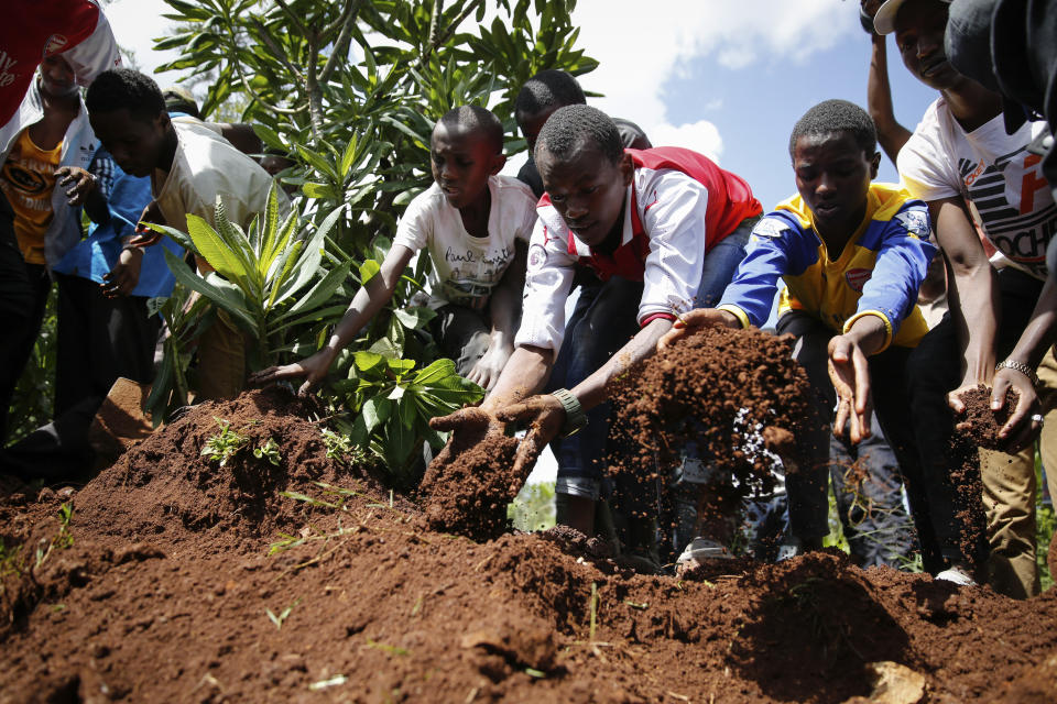 Relatives and friends bury 13-year-old Yasin Hussein Moyo at the Kariakor cemetery in Nairobi, Kenya Tuesday, March 31, 2020. The family of a 13-year-old boy is in mourning after police in Kenya's capital are accused of shooting him dead while enforcing a coronavirus curfew. Kenya’s police inspector general has ordered an investigation into the boy’s death by “stray bullet,” including a forensic analysis of all firearms held by officers at the scene. (AP Photo/Brian Inganga)