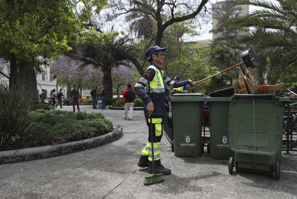 In this Nov. 4, 2019 photo, retired Segundo Vergara, 69, works cleaning the Plaza de Armas in downtown Santiago, Chile. Vergara, who earns 400,000 pesos ($530) a month as a cleaner, said while attending a demonstration in Santiago that if his wife wasn’t working, “we would be living off bread and water, eating rice and pasta every day.” (AP Photo/Esteban Felix)