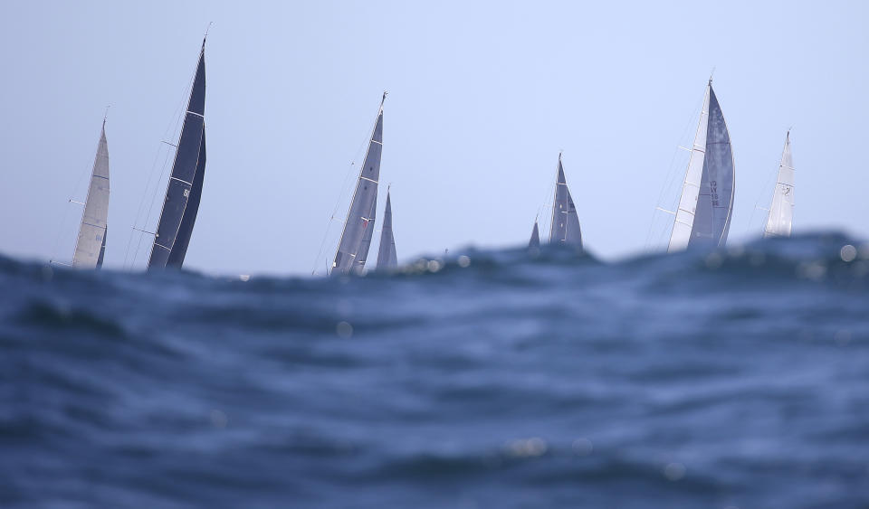 The tops of racing yachts poke above the waves during the start of the Sydney Hobart yacht race in Sydney, Wednesday, Dec. 26, 2018. The 630-nautical mile race has 85 yachts starting in the race to the island state of Tasmania. (AP Photo/Rick Rycroft)