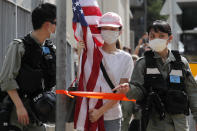 Policías antimotines dan el alto a una manifestante con una bandera estadounidense durante una protesta ante el consulado estadounidense en Hong Kong, el sábado 4 de julio de 2020 por el Día de la Independencia de Estados Unidos. (AP Photo/Kin Cheung)