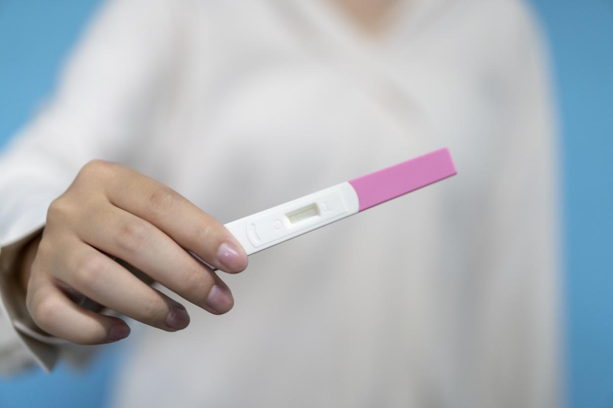 A woman holds a pregnancy test Longhua Liao