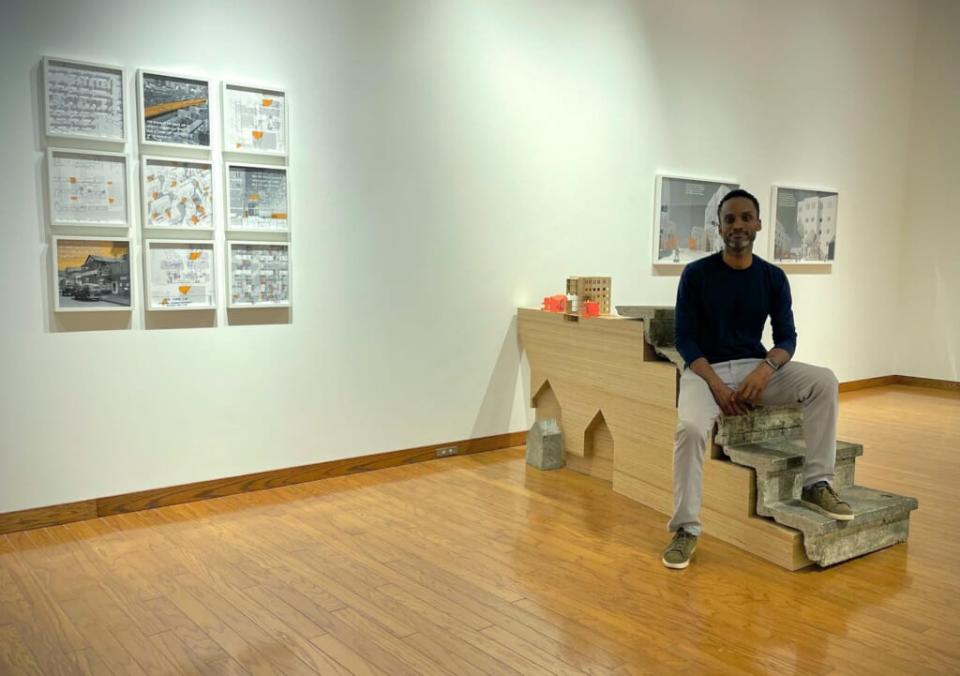 Sekou Cooke sits amid works from We Outchea, a design project of his sekou cooke STUDIO that appeared in the 2021 Museum of Modern Art exhibition, “Reconstructions: Architecture and Blackness in America.” One theme the project explores is the history of the displacement of Syracuse, New York’s Black population through urban renewal projects. (Sekou Cooke/Photo credit: Michelle Schenandoah)