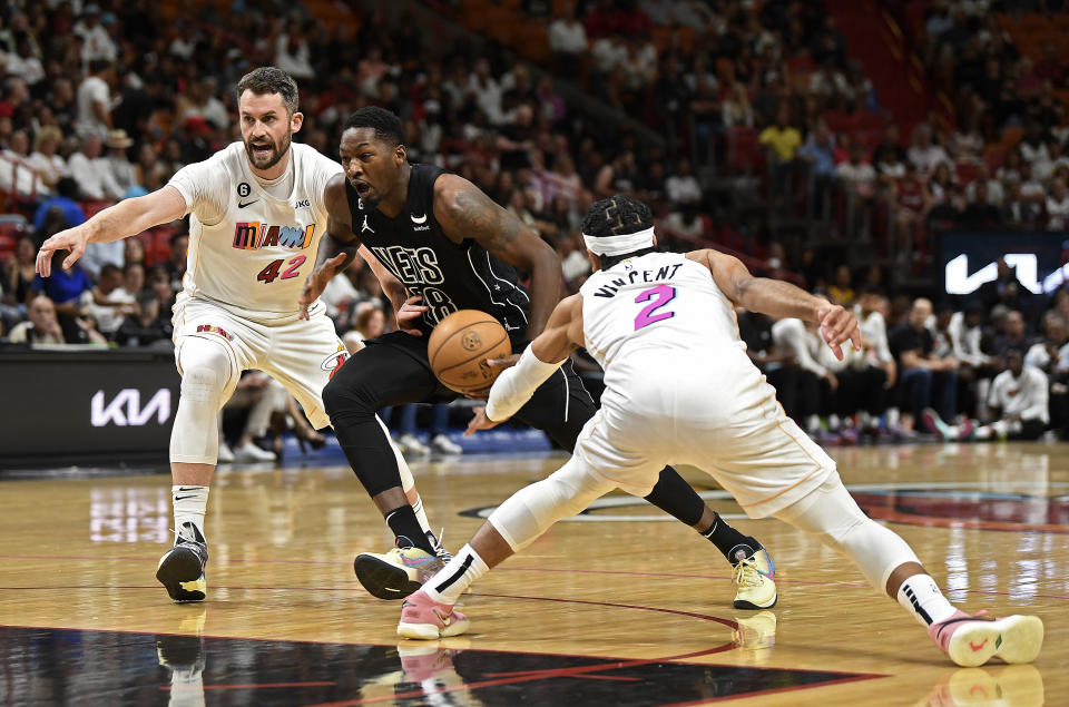 Brooklyn Nets forward Dorian Finney-Smith, center, drives between Miami Heat forward Kevin Love (42) and guard Gabe Vincent (2) during the first half of an NBA basketball game, Saturday, March 25, 2023, in Miami, Fla. (AP Photo/Michael Laughlin)