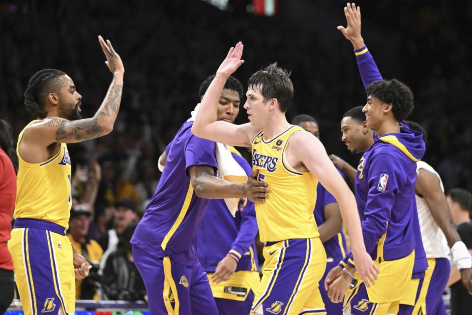 Lakers guard Austin Reaves, center, celebrates with teammates as he heads to the bench during a timeout.