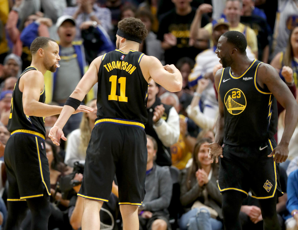 Golden State Warriors' Stephen Curry (30) and Klay Thompson (11) congratulate Draymond Green (23) 