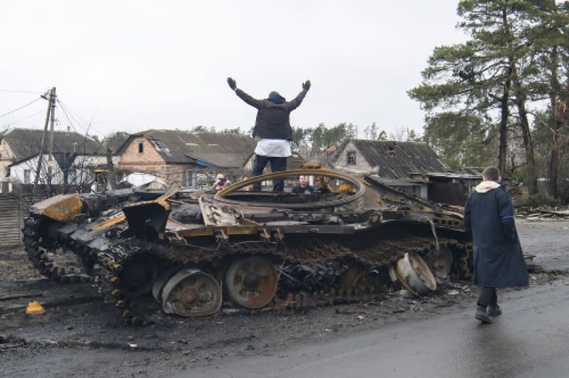 Local residents stand on a destroyed Russian tank in Bucha, Ukraine, on April 2, 2022. On February 24, 2022, after weeks of warnings from the West and Kiev, Russia launched an attack against Ukraine under orders from President Vladimir Putin. File Photo by Vladyslav Musienko/UPI