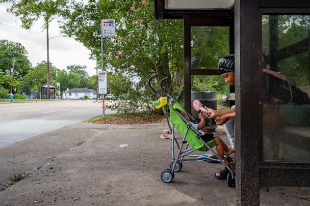 PHOTO: A mother cools her son with a portable fan while waiting for the bus during a heatwave in Houston, July 21, 2022. (Brandon Bell/Getty Images)