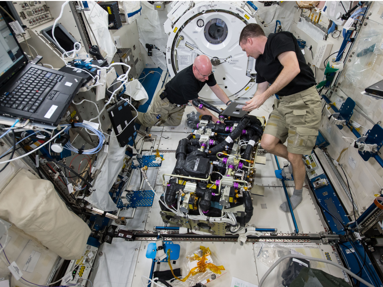 NASA astronauts Scott Kelly (left) and Terry Virts (right) work on a Carbon Dioxide Removal Assembly (CDRA) inside the station’s Japanese Experiment Module (NASA)