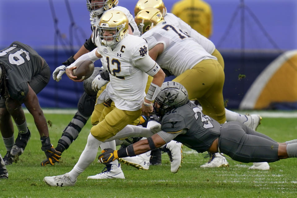 Notre Dame quarterback Ian Book (12) scrambles away from Pittsburgh linebacker SirVocea Dennis (32) for a first down during the first half of an NCAA college football game, Saturday, Oct. 24, 2020, in Pittsburgh. (AP Photo/Keith Srakocic)