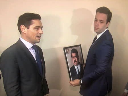 Carlos Vecchio (L), the envoy to the United States of Venezuelan opposition leader Juan Guaido, and an aide take down a picture of Venezuela's President Nicolas Maduro and replace it with a picture of Guaido in this frame grab from video after supporters of Guaido took control of the office of Venezuela's military attache in Washington, U.S. March 18, 2019. REUTERS/Gershon Peaks