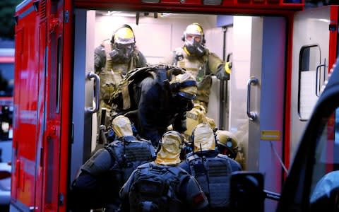 Police officers wearing protective clothes and respiratory masks raid the suspect's flat - Credit: DAVID YOUNG/AFP/Getty Images