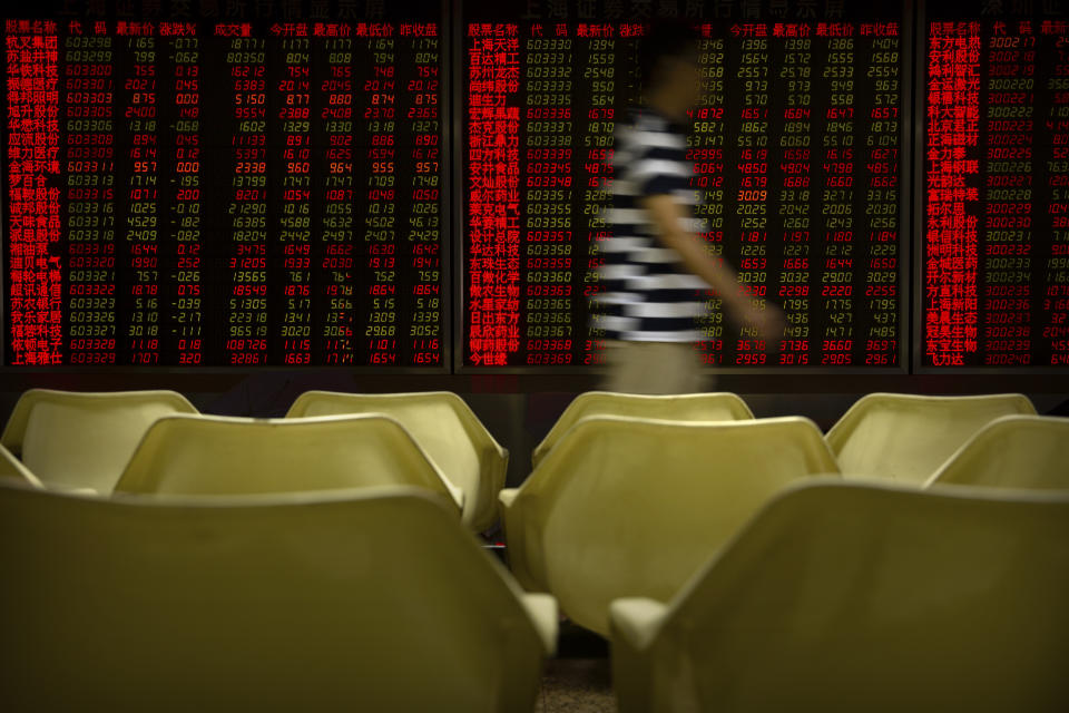 A Chinese investor walks past electronic display boards at a stock brokerage house in Beijing, Tuesday, Aug. 20, 2019. Asian shares were mostly higher Tuesday after Wall Street rallied on the U.S. decision to give Chinese telecom giant Huawei another 90 days to buy equipment from American suppliers. (AP Photo/Mark Schiefelbein)