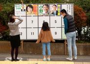 Voters look at posters of candidates for a lower house election, amid the coronavirus disease (COVID-19) pandemic, outside a polling station in Tokyo