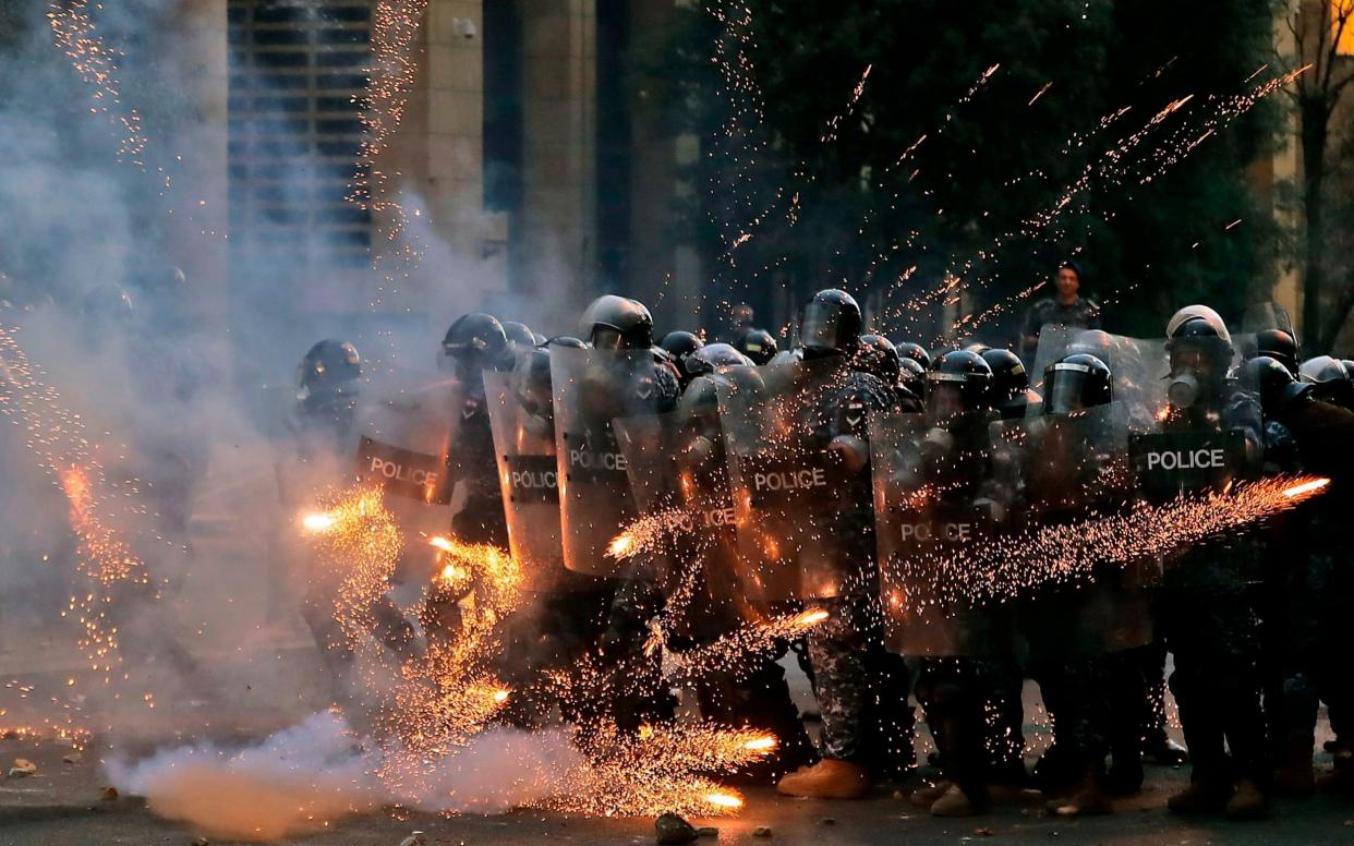 Firecrackers thrown by protesters explode in front of riot police amid clashes in the vicinity of the parliament in central Beirut 