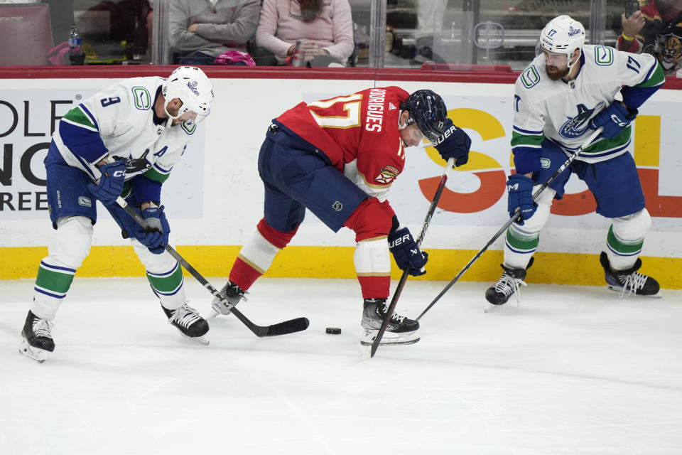 Florida Panthers center Evan Rodrigues (17) battles for the puck with Vancouver Canucks center J.T. Miller (9) and defenseman Filip Hronek, right, during the second period of an NHL hockey game, Saturday, Oct. 21, 2023, in Sunrise, Fla. (AP Photo/Wilfredo Lee)