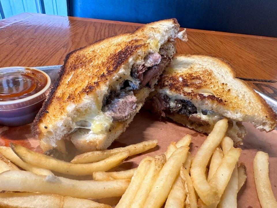 The Brisket Melt from Top Hog BBQ comes topped with smoked brisket, melted cheddar and gouda cheese, and a horseradish cream on grilled sourdough bread.