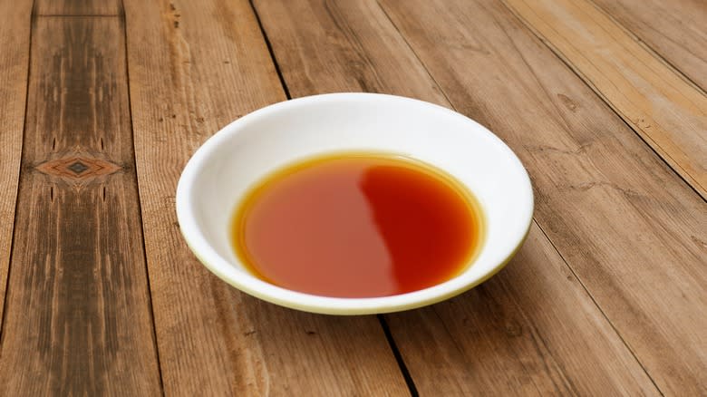Dish with fish sauce on wood background