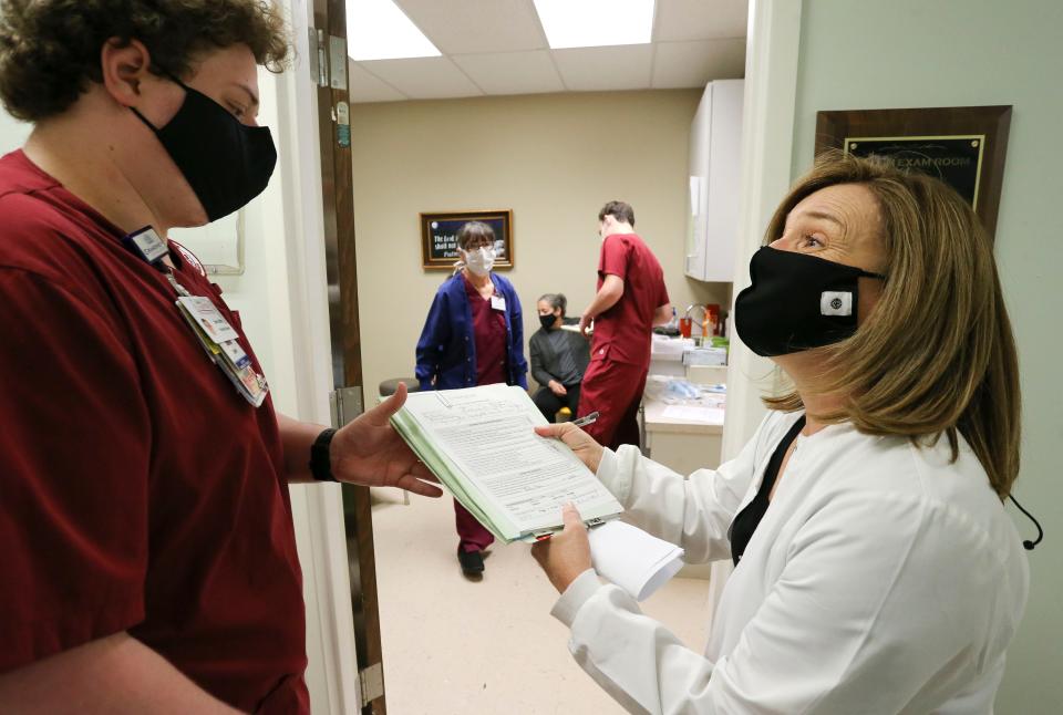 Michelle Cheshire, a registered nurse and professor in the College of Nursing, signs off on a vaccination form for student Sam Griffin at the Good Samaritan Clinic in Northport on Feb. 25, 2021. [Staff Photo/Gary Cosby Jr.]