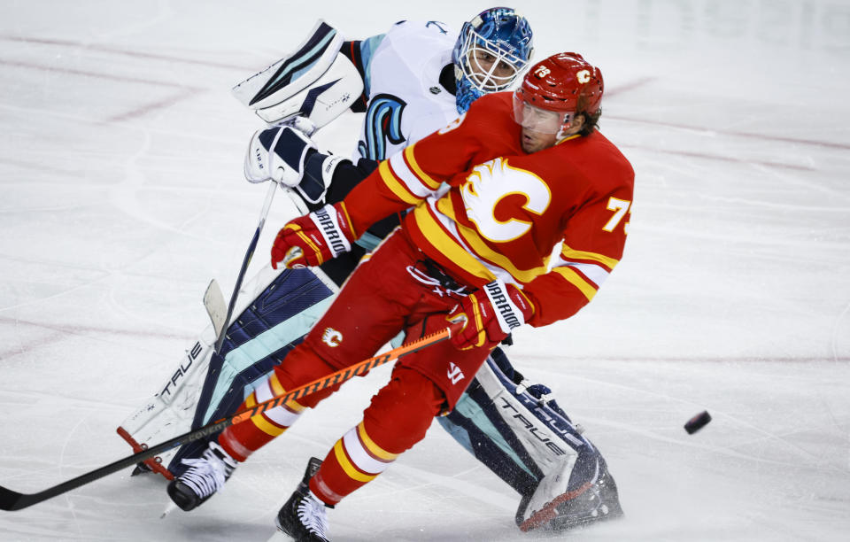 Seattle Kraken goalie Joey Daccord, left, comes out the crease to play the puck as Calgary Flames forward Tyler Toffoli crashes into him during the third period of an NHL hockey game, Tuesday, Nov. 1, 2022 in Calgary, Alberta. (Jeff McIntosh/The Canadian Press via AP)