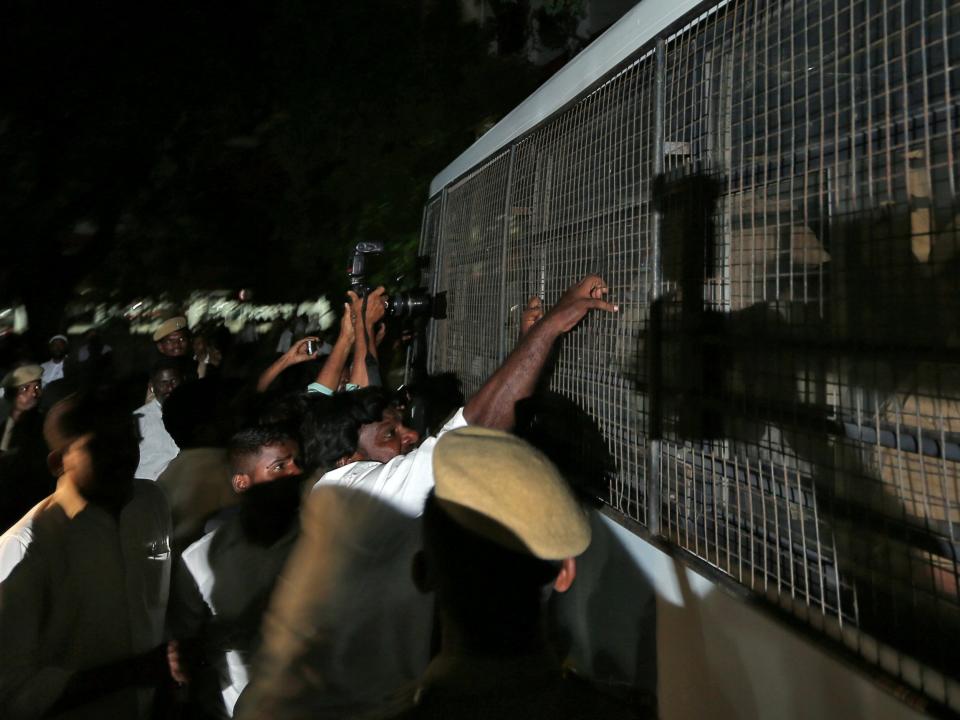 A lawyer attempts to pull the fenced window of a police vehicle carrying men (unseen) accused of raping a 12-year girl inside the high court premises in Chennai: REUTERS