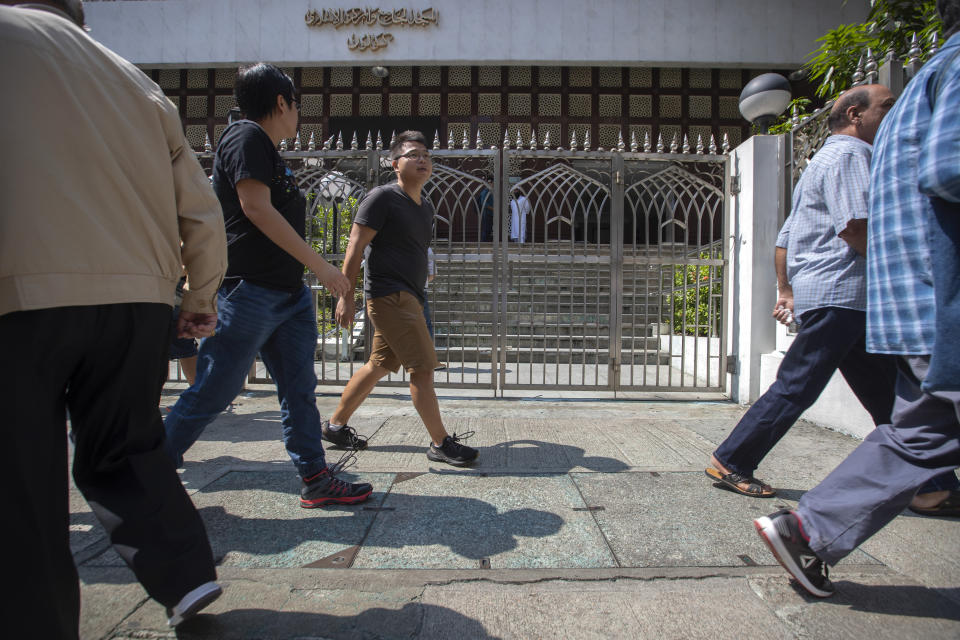 Pedestrians walk past a blue-stained sidewalk outside the Kowloon Mosque a day after it was sprayed with blue-dyed water by a police riot-control vehicle in Hong Kong, Monday, Oct. 21, 2019. Hong Kong officials apologized to leaders of the Kowloon Mosque after riot police sprayed the building's gate and some people nearby with a water cannon as they tried to contain pro-democracy demonstrations. (AP Photo/Mark Schiefelbein)