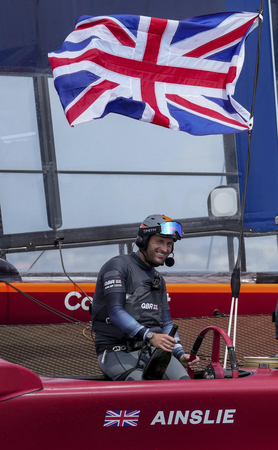 In this photo provided by SailGP, Sir Ben Ainslie holds a bottle and the Britain SailGP Team presented by INEOS remain on their F50 due to COVID-19 restrictions to celebrate their win in the final race on race Day 2 of the Bermuda SailGP event in Hamilton, Bermuda, Sunday, April 25, 2021. (Bob Martin/SailGP via AP)