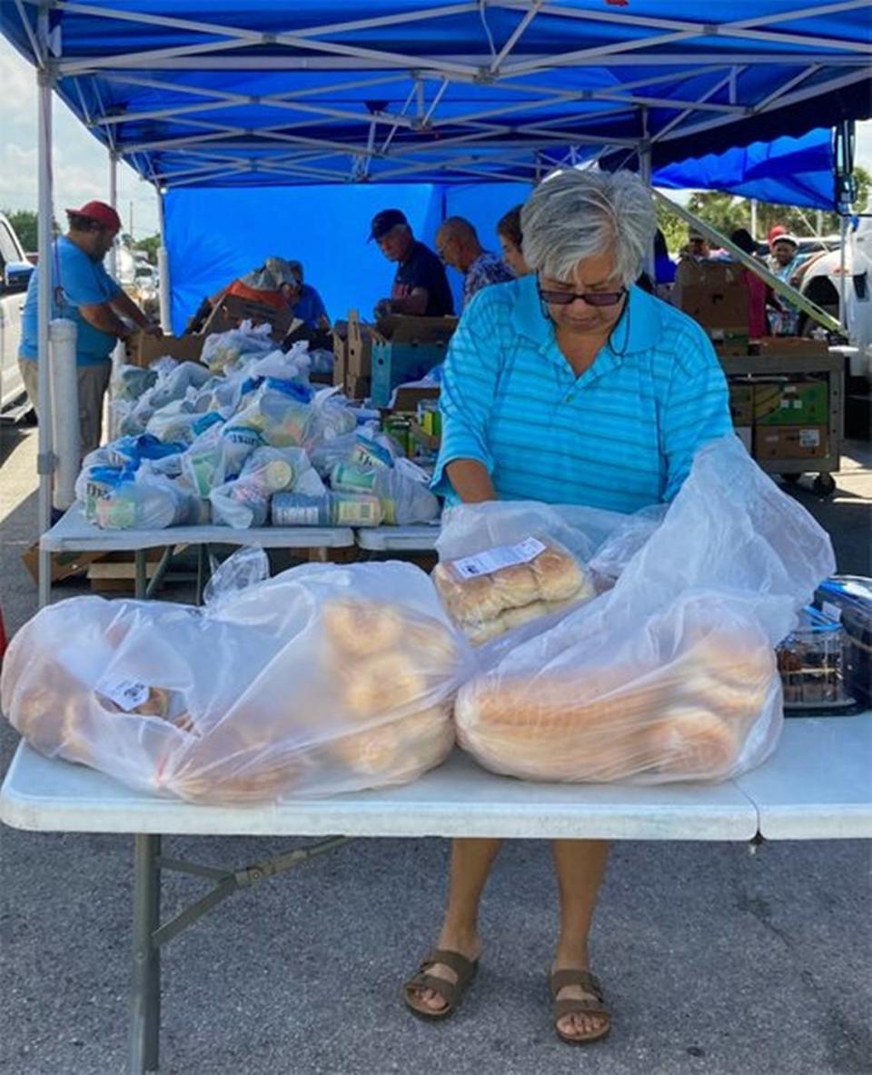 Una voluntaria distribuye bolsas de comida gratis en la distribución semanal de los jueves de Meals of Hope en el Farmworker Village de Immokalee.