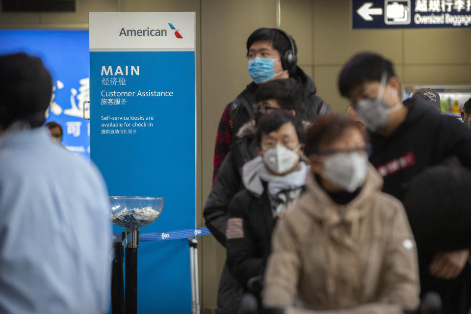 Travelers wearing face masks line up to check in for an American Airlines flight to Los Angeles at Beijing Capital International Airport in Beijing, Thursday, Jan. 30, 2020. China counted 170 deaths from a new virus Thursday and more countries reported infections, including some spread locally, as foreign evacuees from China's worst-hit region returned home to medical observation and even isolation. (AP Photo/Mark Schiefelbein)