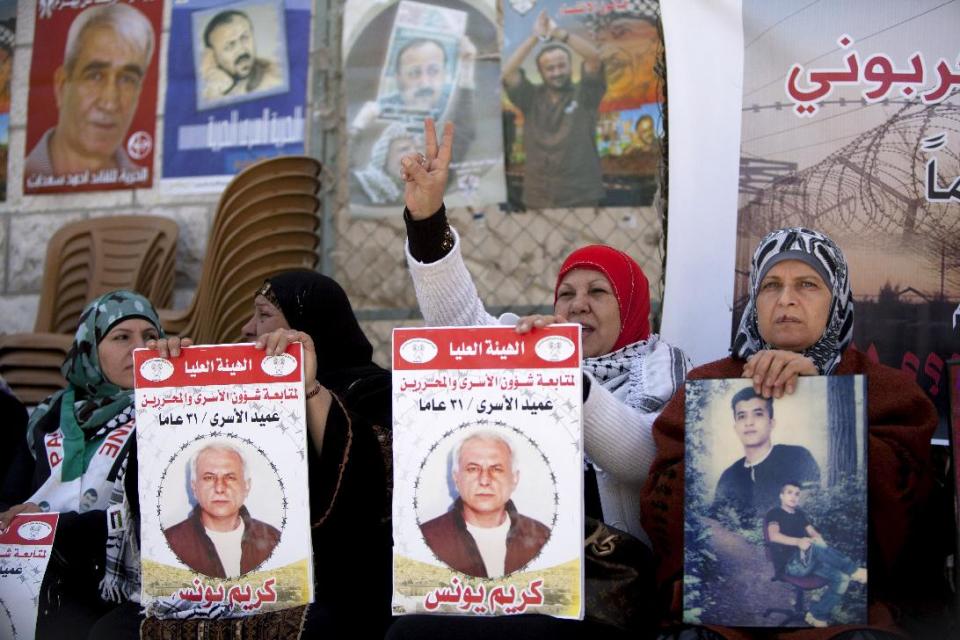 Women hold portraits of Palestinian prisoners held in Israeli jails during a rally calling for their release in the West Bank city of Ramallah, Tuesday, April 1, 2014. Arabic on the posters read, "Dean of prisoners, Karim Younis, 21 years in prison." (AP Photo/Majdi Mohammed)