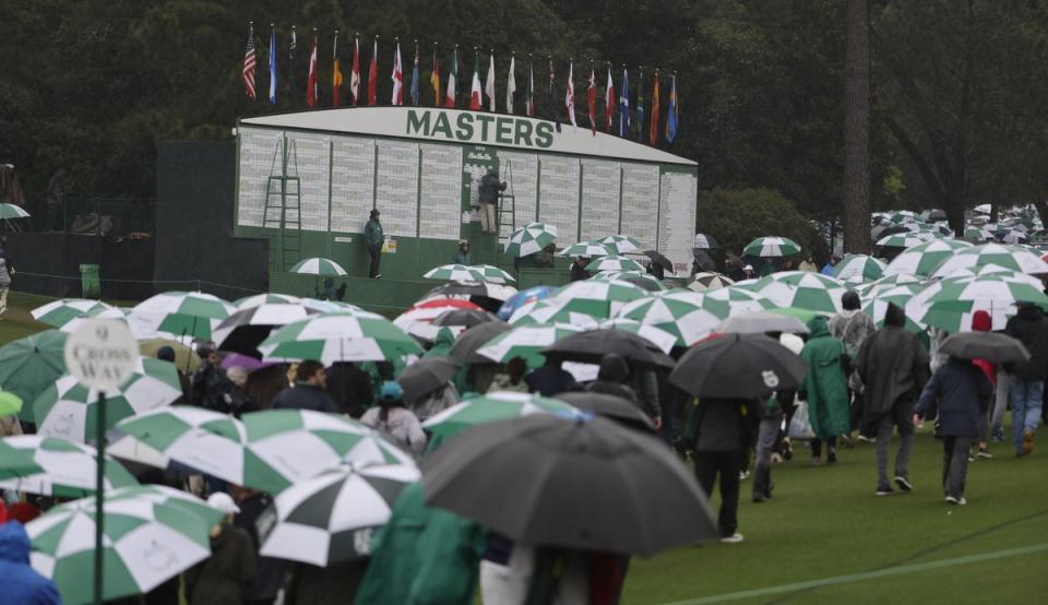 Patrons make their way past the leaderboard following the suspension of play in the third round of the Masters Tournament (EPA)