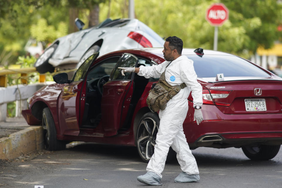A forensic medical examiner work at the scene where an unidentified man was killed in Apatzingan, Mexico, Sunday, July 2, 2023. Apatzingan, the regional hub where the area's agricultural products are traded, gunmen carjacked a family, took their auto at gunpoint and used it to shoot another driver to death just a few blocks away. (AP Photo/Eduardo Verdugo)