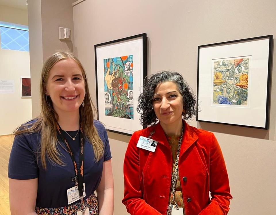 Stephanie Toole and Alexandra Nicholis Coon, both of the Massillon Museum, stand near artwork in the new exhibit, "Un-settling: A Story of Land Removal and Resistance."