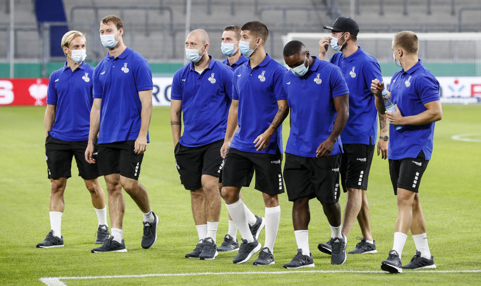 FILE-This Sept. 14, 2021 taken photo shows Duisburg's players arrive with face masks due to the coronavirus rules on the pitch prior the 1st round German Soccer Cup match between MSV Duisburg and Borussia Dortmund in Duisburg, Germany. The German soccer league says more than 90% of players, coaches and staff from the 36 clubs in the Bundesliga and second division have received vaccines against the coronavirus. (AP Photo/Martin Meissner)