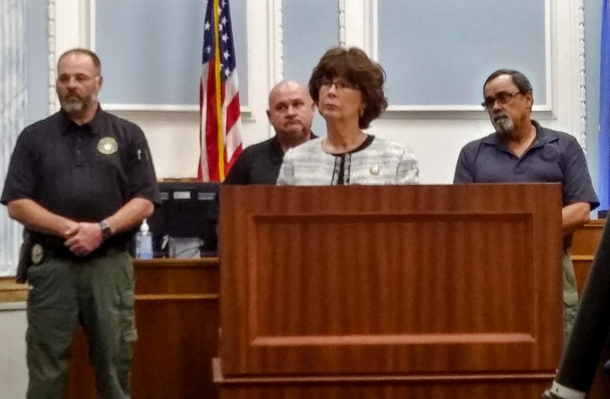 Okmulgee County District Attorney Carol Iski (photo center foreground) formally announces murder charges on Monday against Joseph Lloyd Kennedy in a case involving four men found shot and dismembered in the nearby Deep Fork River in October.