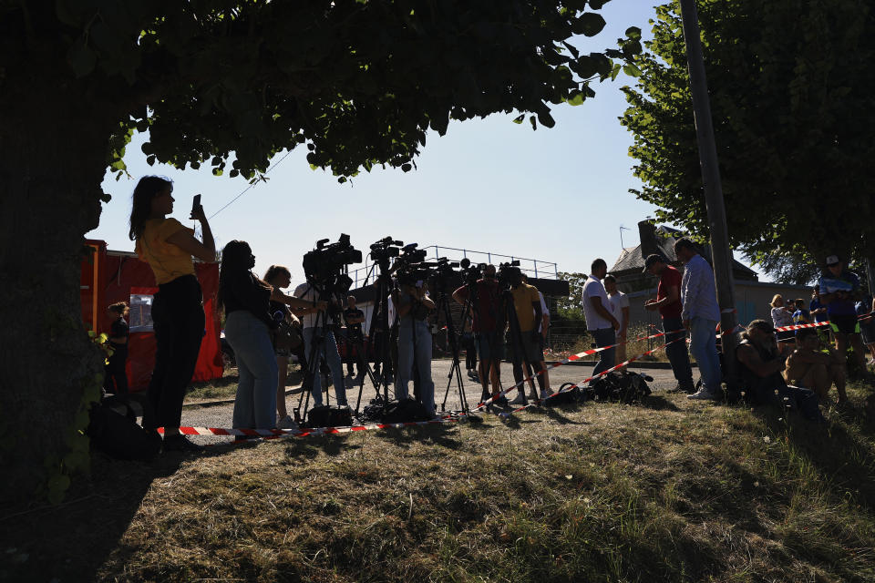 News members and onlookers wait near the lock of Notre Dame de la Garenne where a Beluga whale is being prepared to be moved, in Saint-Pierre-la-Garenne, west of Paris, France, Tuesday, Aug. 9, 2022. French environmentalists are moving a dangerously think Beluga that had strayed into the Seine River last week to a salt-water river basin to try and save its life. Lamya Essemlali, president of Sea Shepherd France, said the ethereal white mammal measuring 4-meters will be transported to the salty water for "a period of care" by medics who suspect the mammal is sick. (AP Photo/Aurelien Morissard)