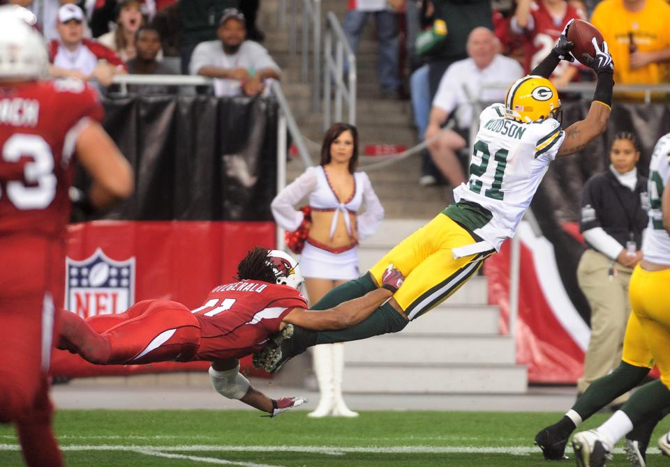 Arizona Cardinals wide receiver Larry Fitzgerald attempts to stop Green Bay Packers cornerback Charles Woodson as he leaps into the end zone for a touchdown.