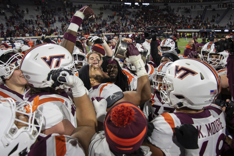 Virginia Tech players drink from the Commonwealth Cup after defeating Virginia 55-17 in an NCAA college football game Saturday, Nov. 25, 2023, in Charlottesville, Va. (AP Photo/Mike Caudill)