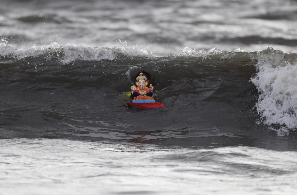A devotee immerses an idol of Hindu god Ganesha on the fifth day of the ten-day long Ganesh Chaturthi festival in the Arabian sea in Mumbai, India, Wednesday, Aug. 26, 2020. The festival is a celebration of the birth of Ganesha, the Hindu god of wisdom, prosperity and good fortune. (AP Photo/Rajanish Kakade)
