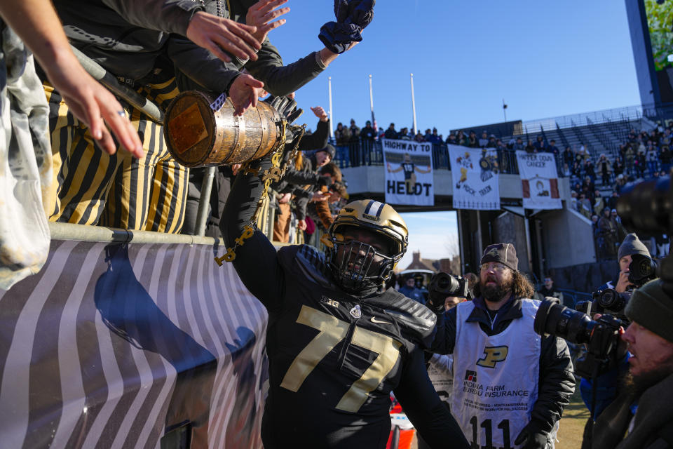 Purdue offensive lineman Mahamane Moussa (77) carries the Old Oaken Bucket as he celebrates with fans after Purdue defeated Indiana in an NCAA college football game in West Lafayette, Ind., Saturday, Nov. 25, 2023. Purdue defeated Indiana 35-31. (AP Photo/Michael Conroy)