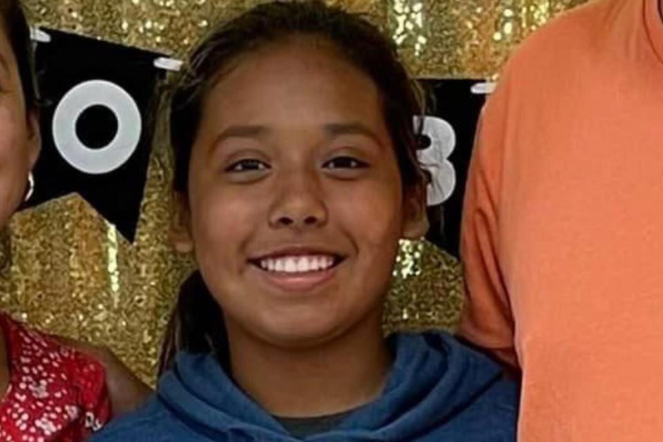 A closeup of a girl smiling against a glittery gold backdrop