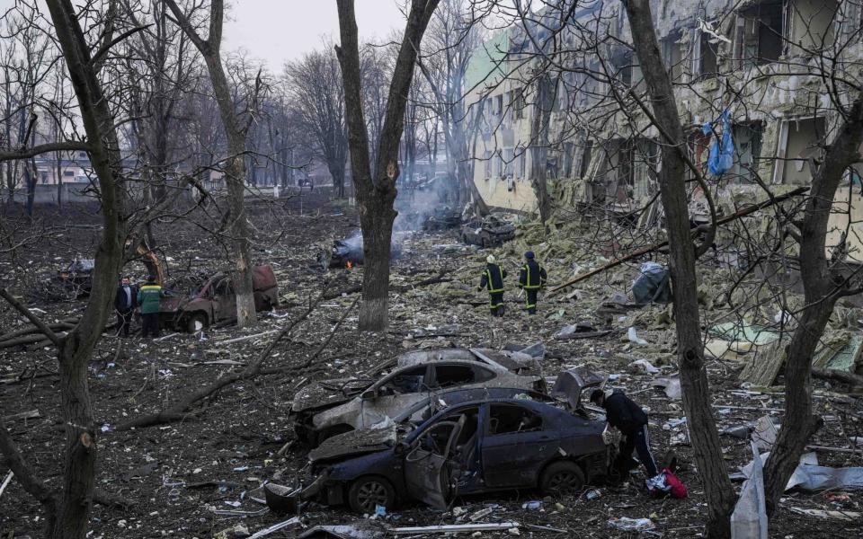 Ukrainian rescue teams sift through the rubble of the maternity hospital in Mariupol - AP