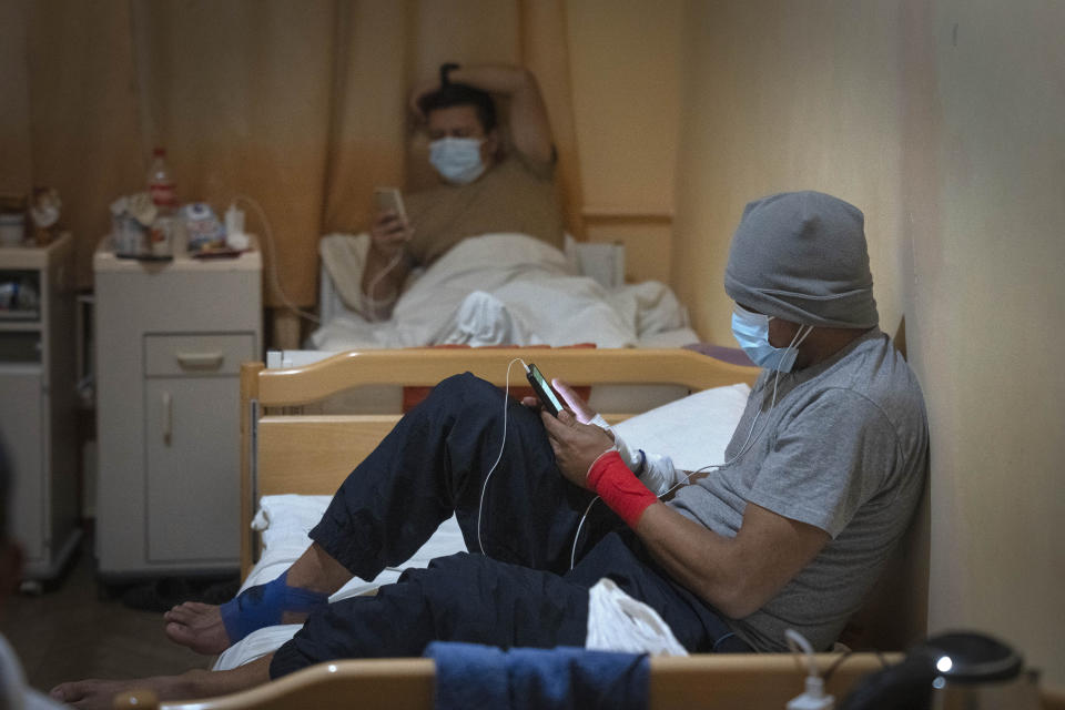 Wounded Colombian veterans, who joined the Ukrainian armed forces to help fight Russia, look at their phones in a hospital in Ukraine, Wednesday, Dec. 20, 2023. After two years of war, Ukraine is looking for ways to replenish its depleted ranks, and the Colombian professional soldiers are a welcome addition. (AP Photo/Efrem Lukatsky)