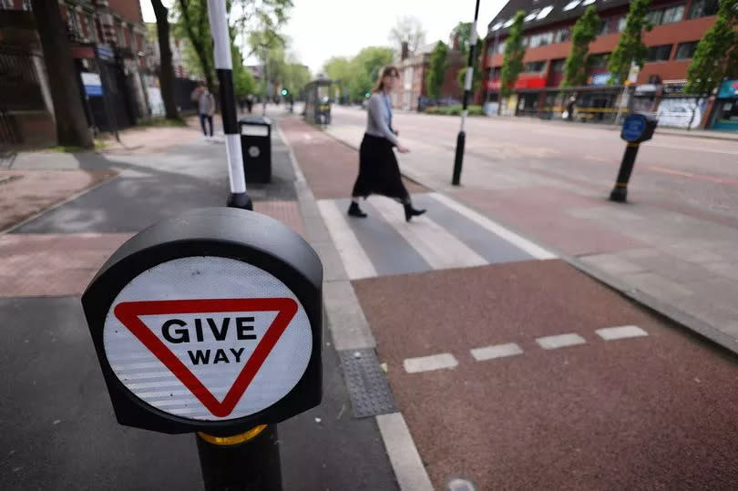 Pedestrian going over the crossing over the cycle lane on Oxford Road