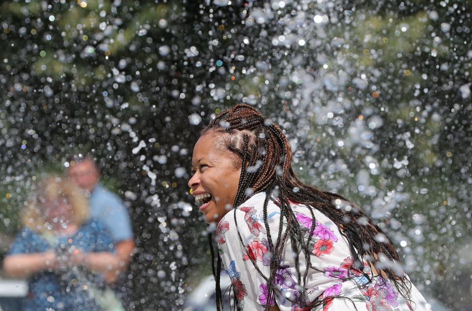 Akron City Councilwoman Tara Mosley plays in the water in August 2019 at the opening of Akron's first splash pad at Joy Park Community Center