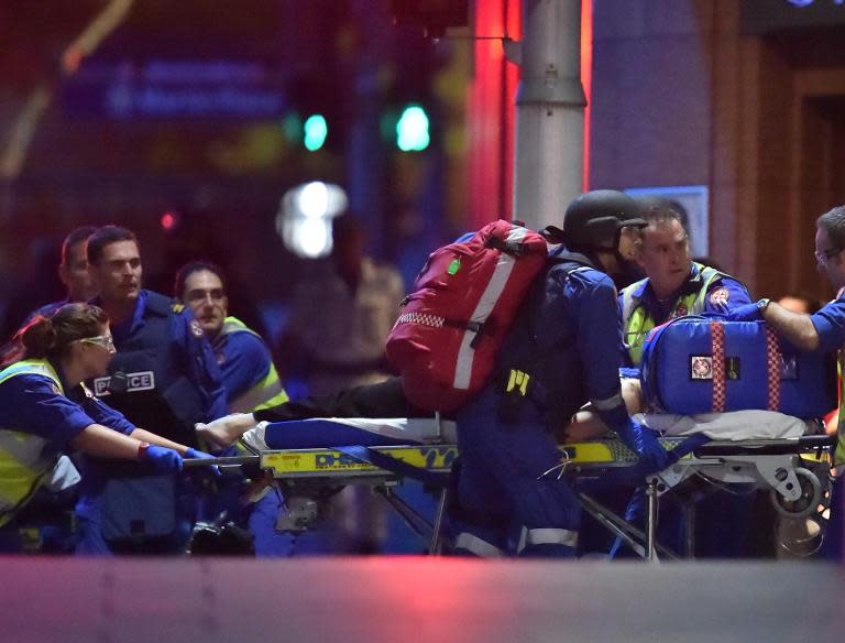 Australian paramedics work on an injured hostage as people are rescued from a cafe where they were held captive by Man Haron Monis in Sydney on December 16, 2014