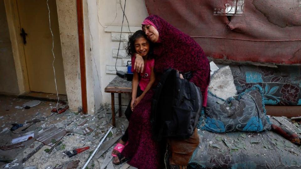 Una madre palestina abraza a su hija en su casa que quedó gravemente dañada tras un ataque israelí.