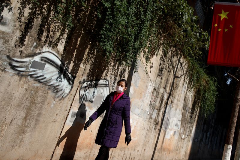 A woman wearing a face mask walks past a Chinese flag in Changsha